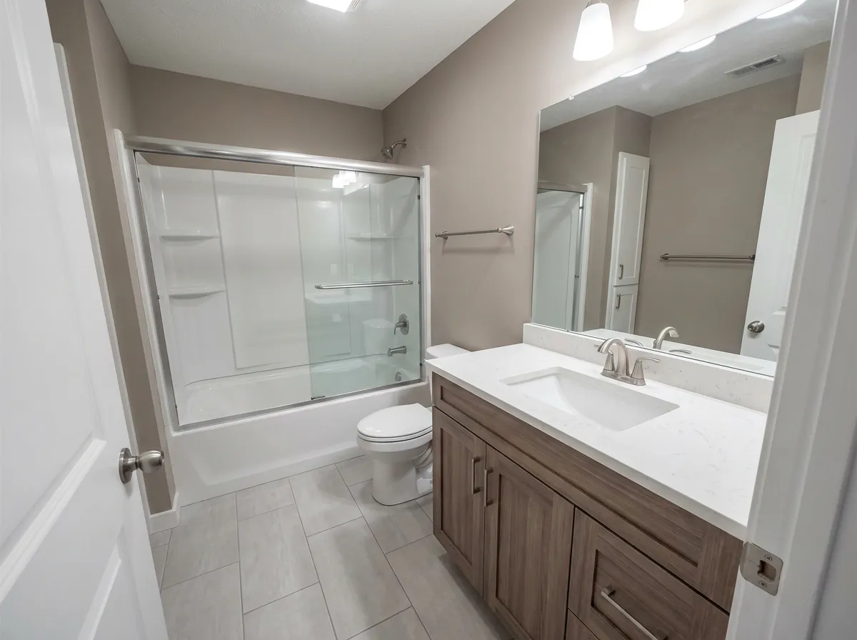 Full bathroom renovation with wood vanity, quartz top, and tub-shower combo by Magee Homes