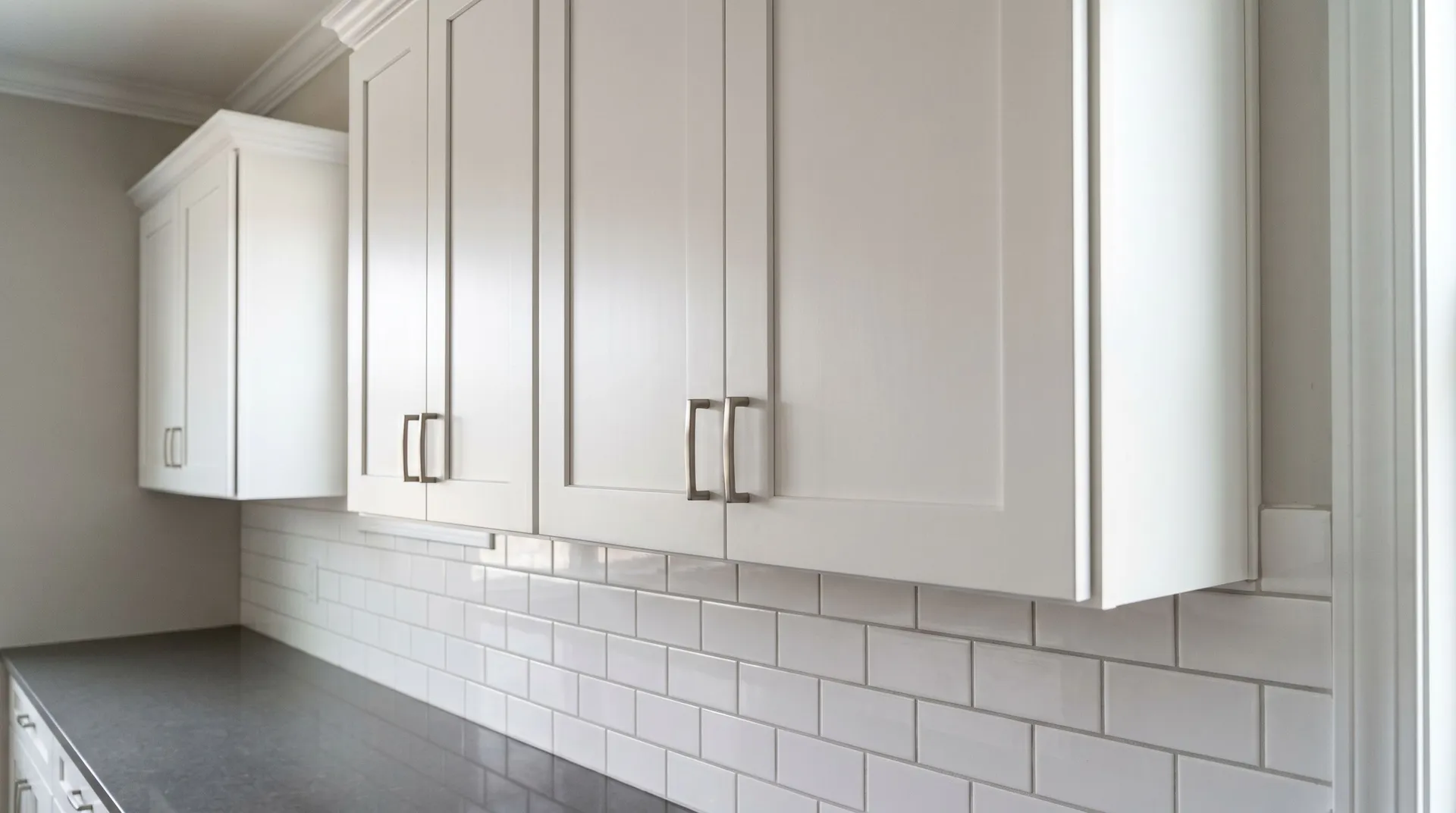 White shaker kitchen cabinets with brushed nickel pulls, white subway tile backsplash, and gray quartz countertop by Magee Homes in Connecticut